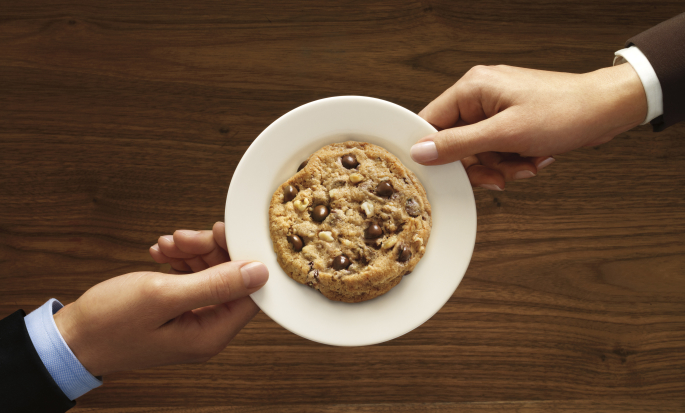 Two Hands Holding White Plate With a Cookie